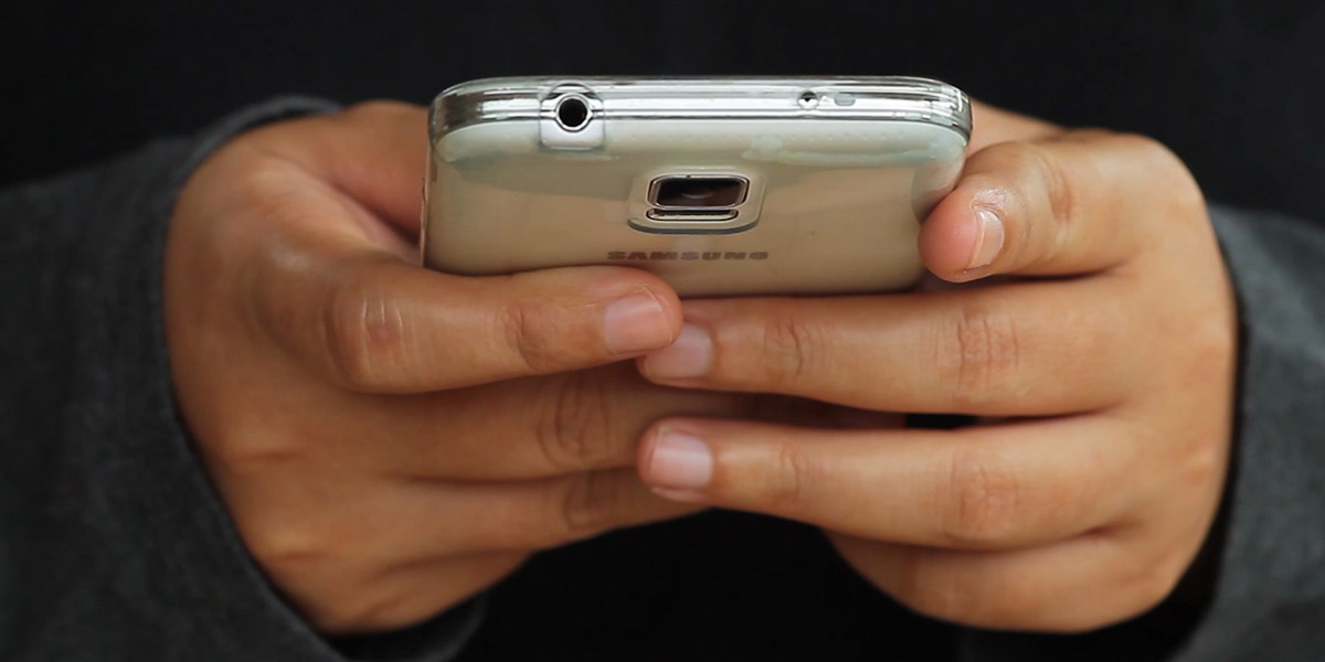 A closeup of a pair of hands typing on a Samsung smart phone