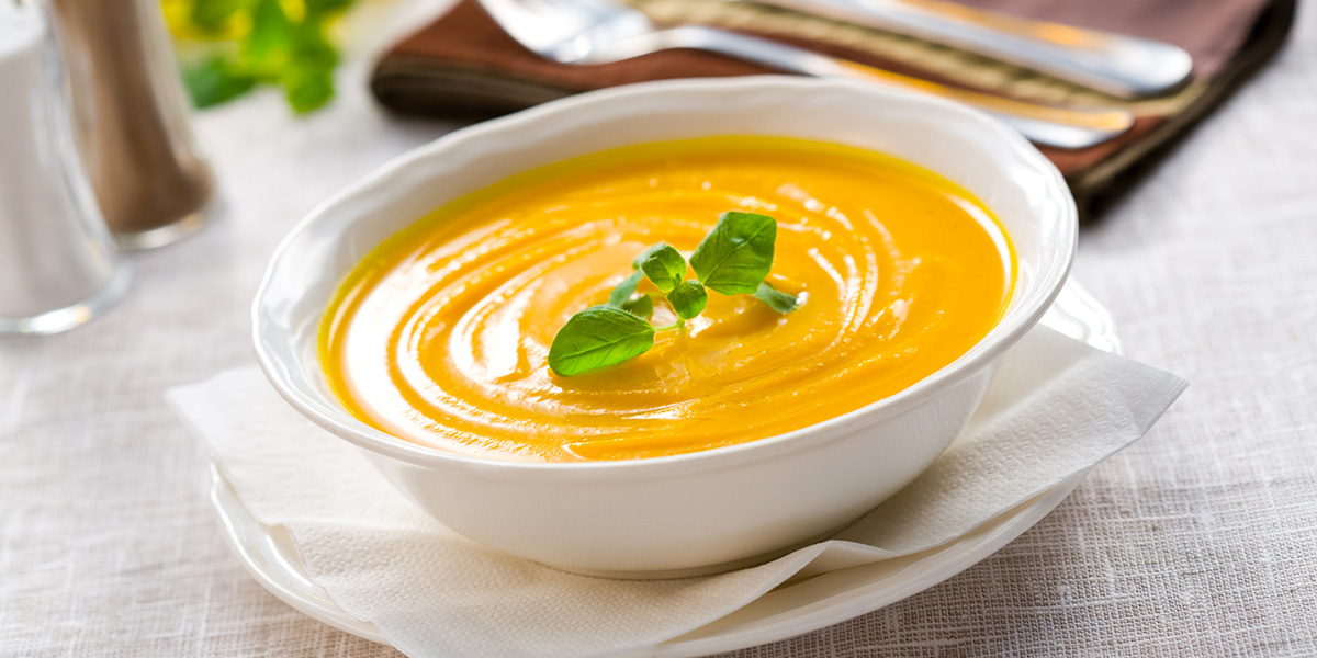 White bowl of pumpkin soup with garnish