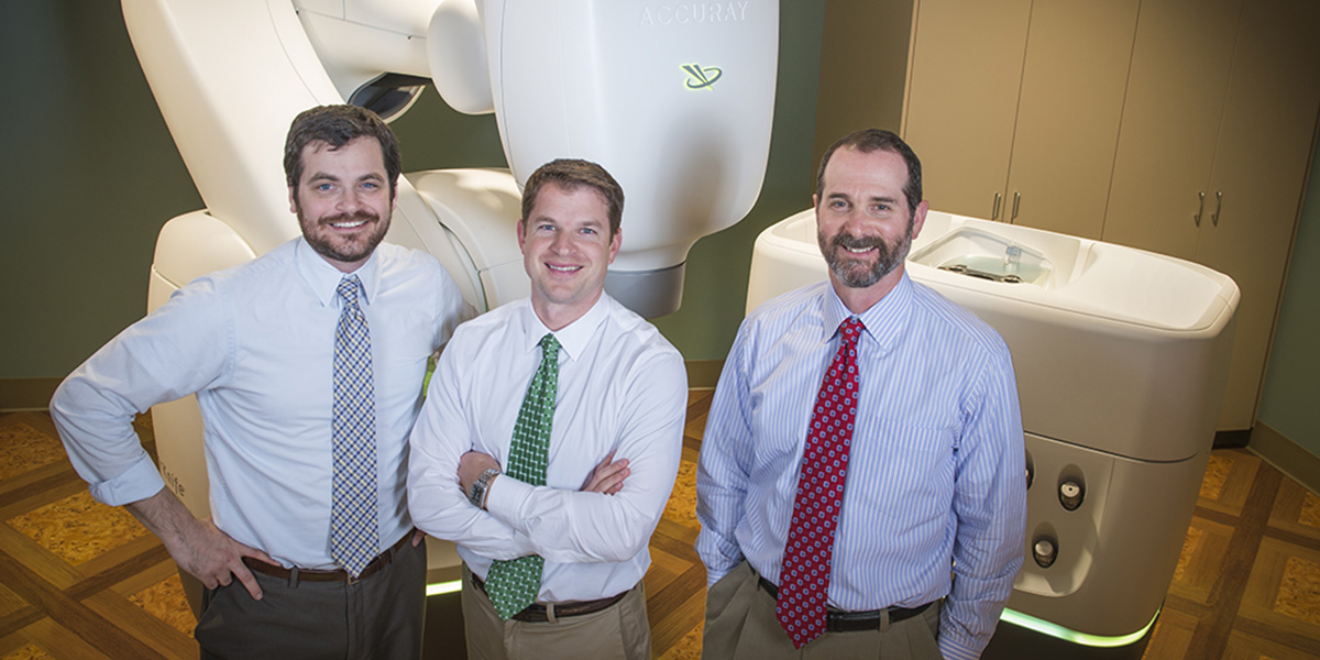 Jacob Gersh, PhD, Jeremy Kilburn, MD and Daniel Fried, MD pose with the CyberKnife M6 Series Radiosurgery System at Gibbs Cancer Center & Research Institute—Pelham in Greer, SC