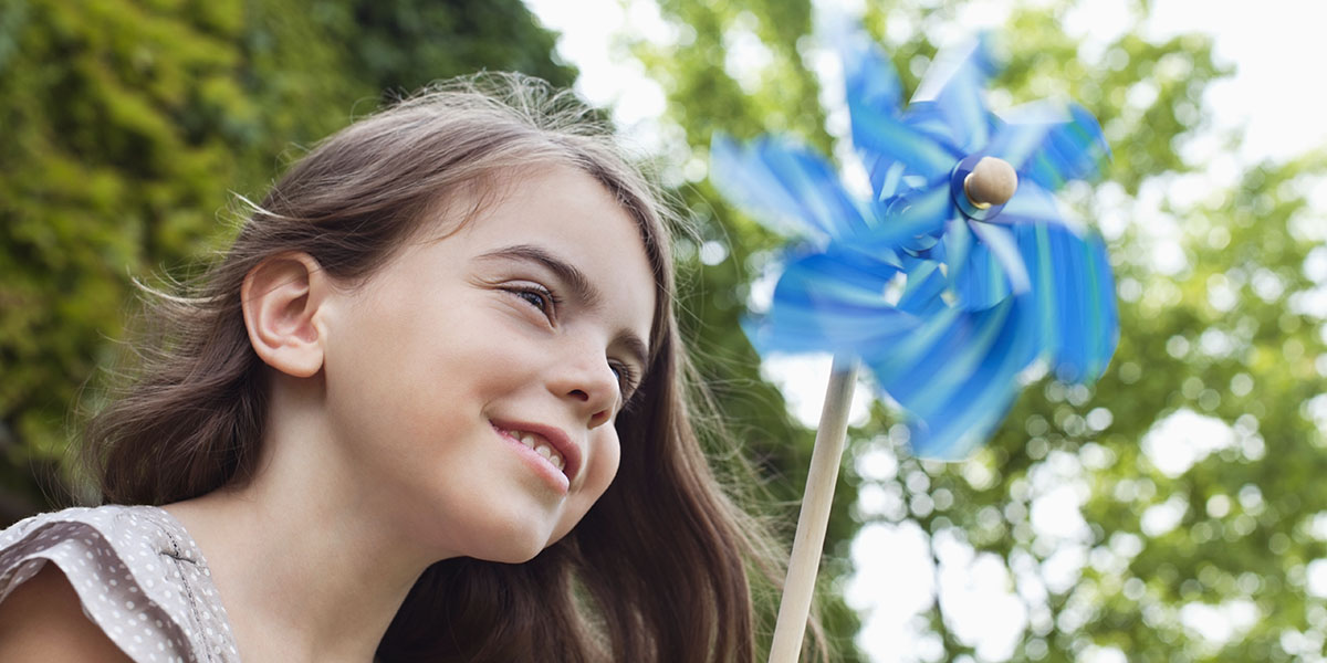 Smiling girl holding pinwheel outdoors