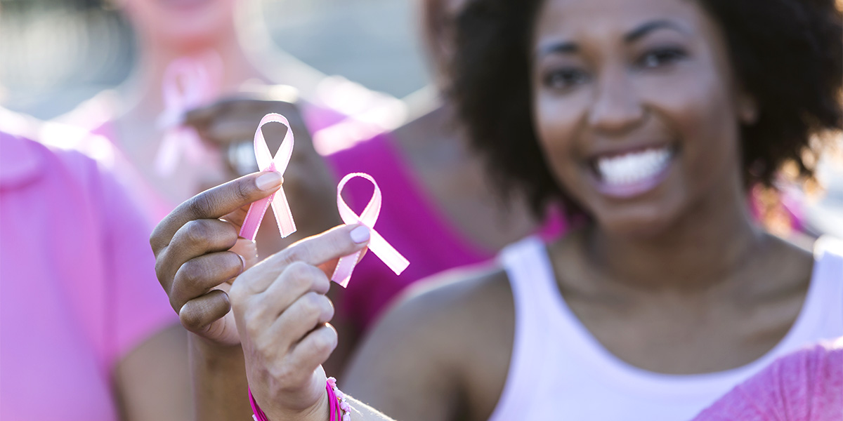 Multiracial women holding breast cancer awareness ribbon