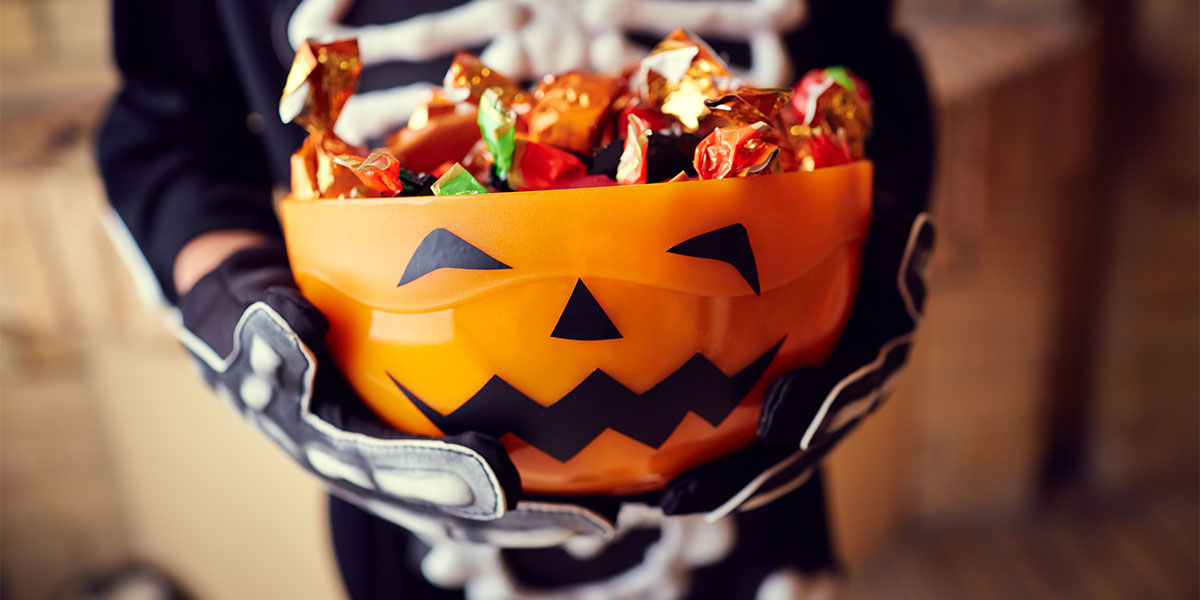 Boy in skeleton costume holding bowl full of candies