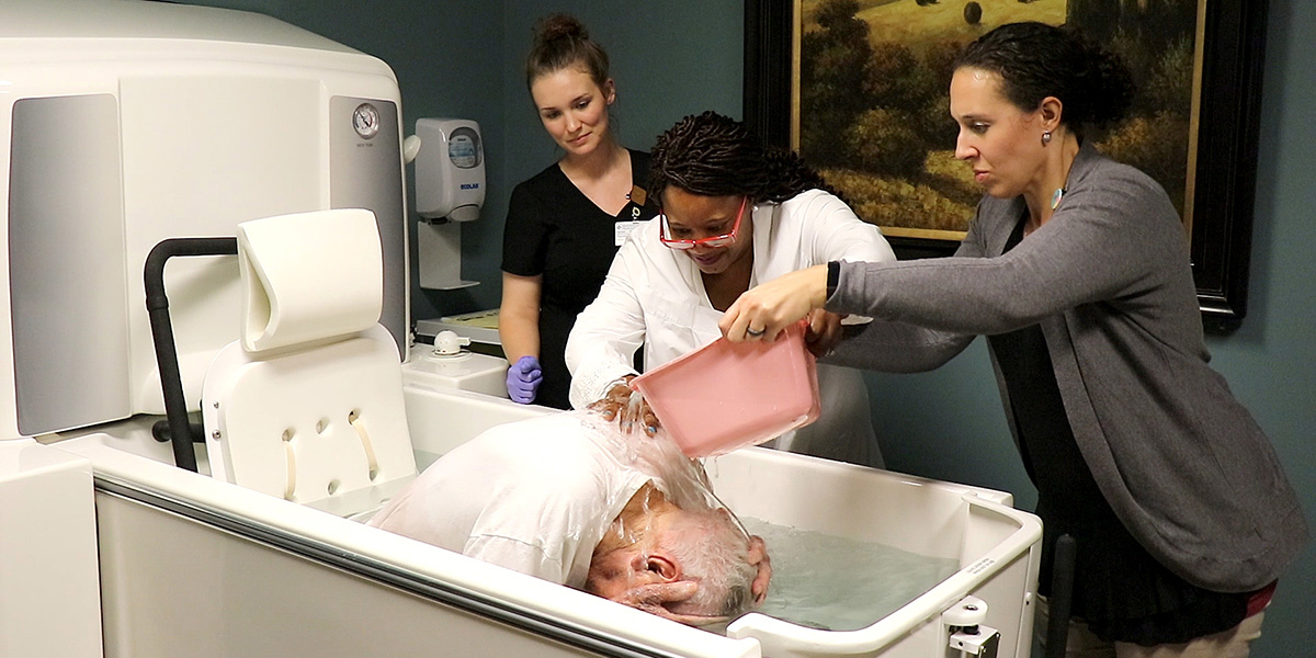 Hospice patient Jenis James Grindstaff is being baptized by a chaplain in a special tub