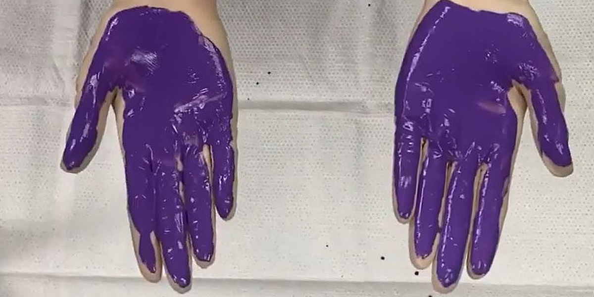 Hands with purple paint on them used to demonstrate how to properly wash for 20 seconds