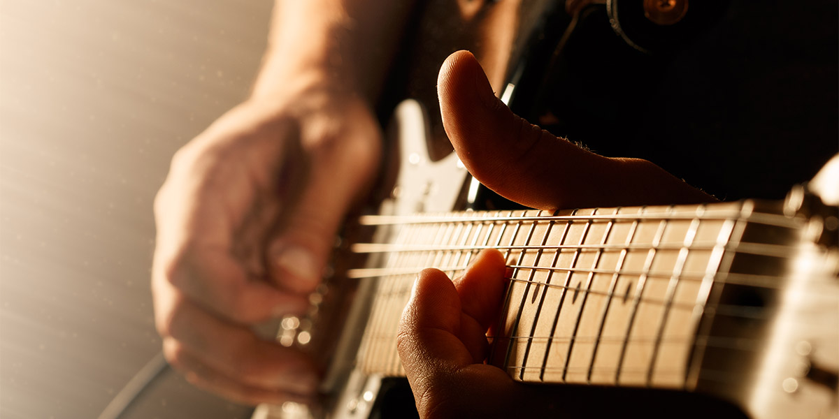 Close up of mans fingers playing electric guitar