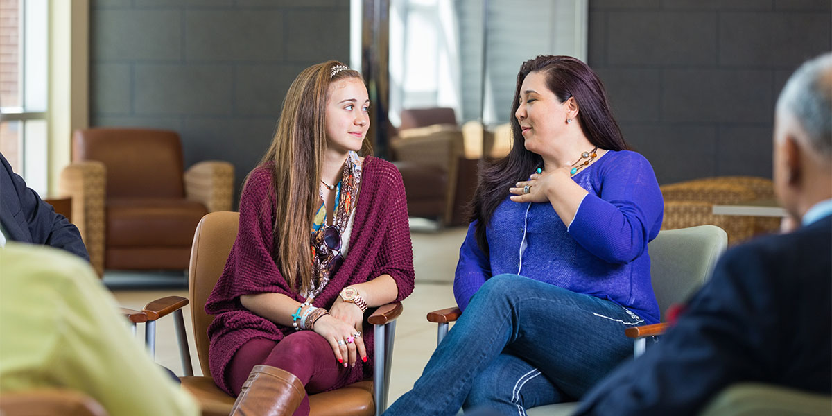 Woman and teenager talking during diverse support group meeting