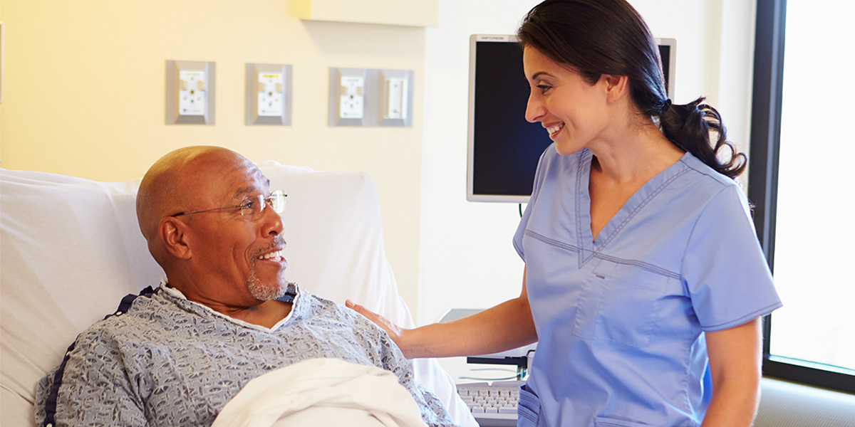 Nurse Talking To Senior Male Patient In Hospital Room