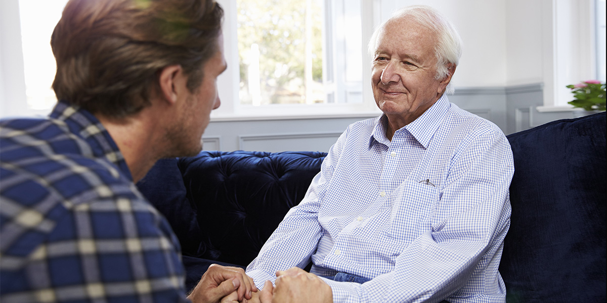 Adult Son Talking To Depressed Father At Home