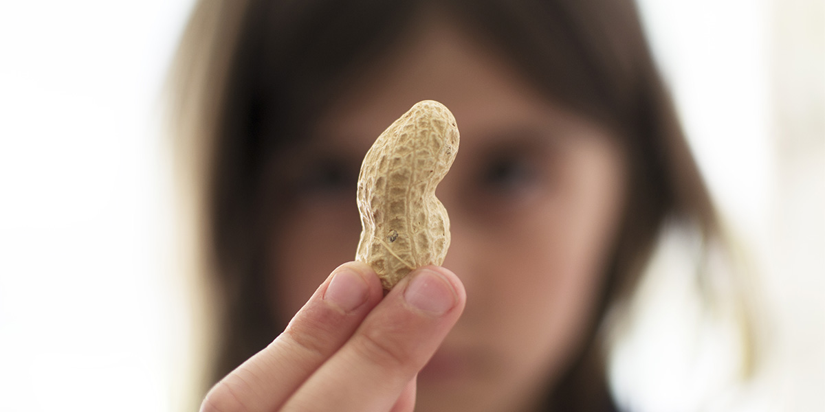 A young girl holding up a nut and looking sad