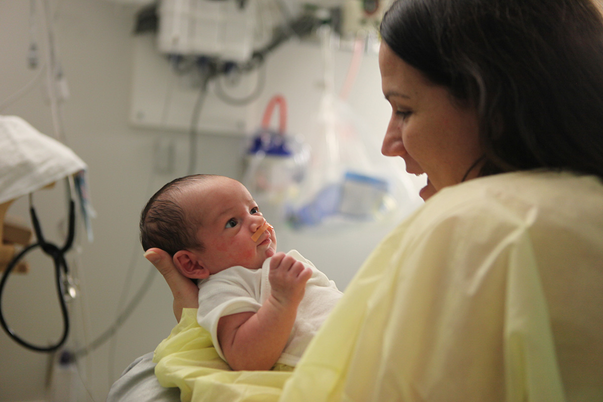 A new mother in a hospital gown holds her infant in Spartanburg Regional Neonatal Intensive Care Unit (NICU).jpg