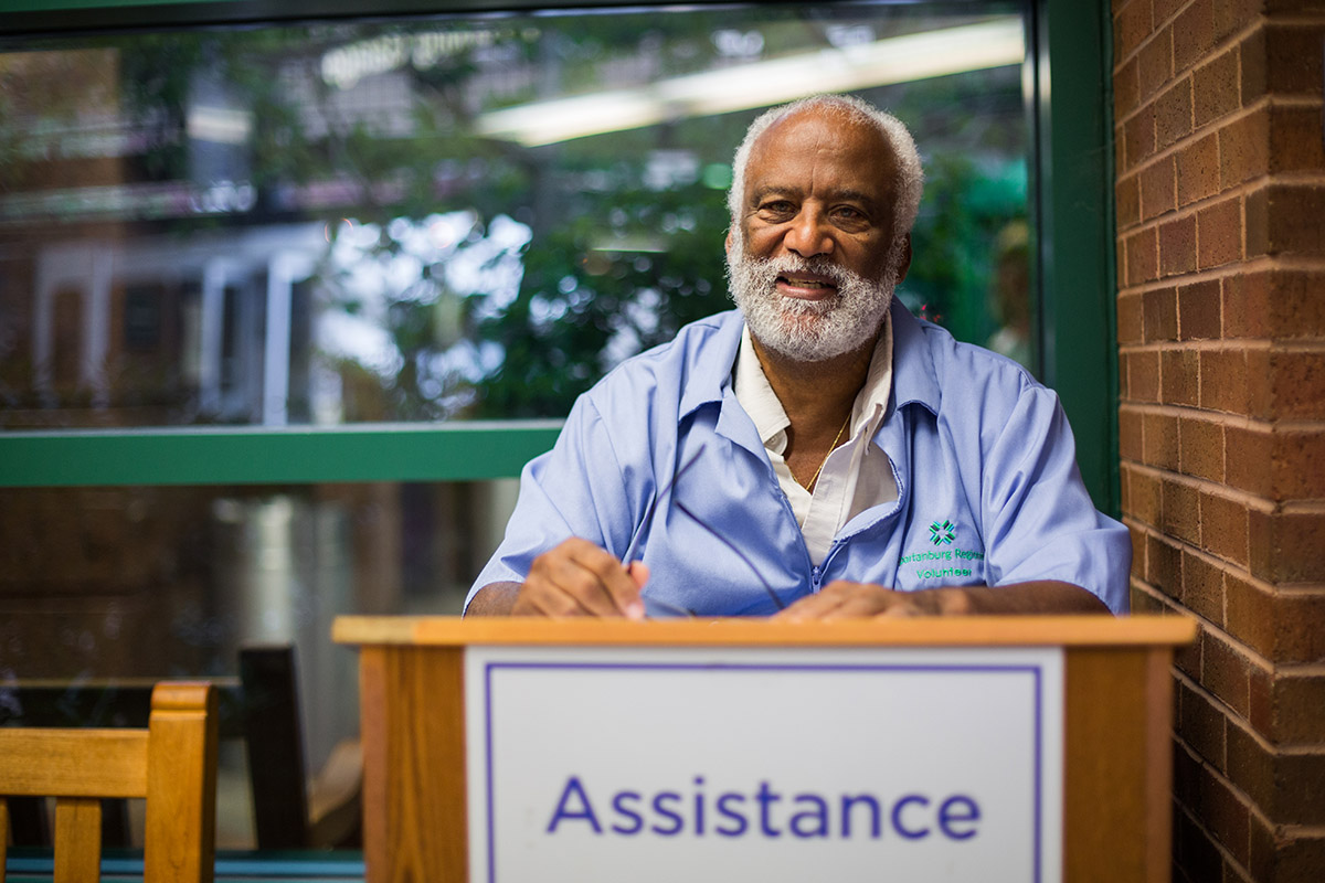 A photo of a mature man with a beard dressed in a spartanburg regional volunteer jacket smiles at the camera.jpg