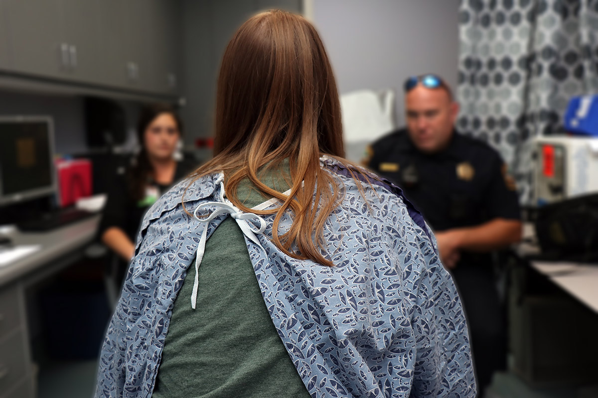 An unidentifiable sexual trafficking victim sits with her back to the camera and discusses the aftermath assault with members of law enforcement.jpg