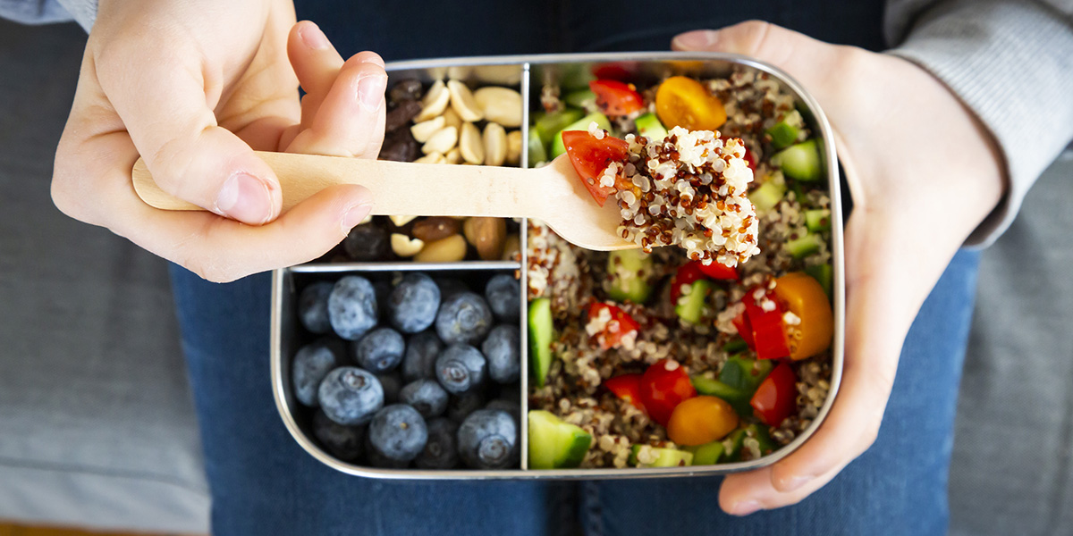 Lunchbox with quinoa salad with tomato and cucumber, blue berry and trail mix