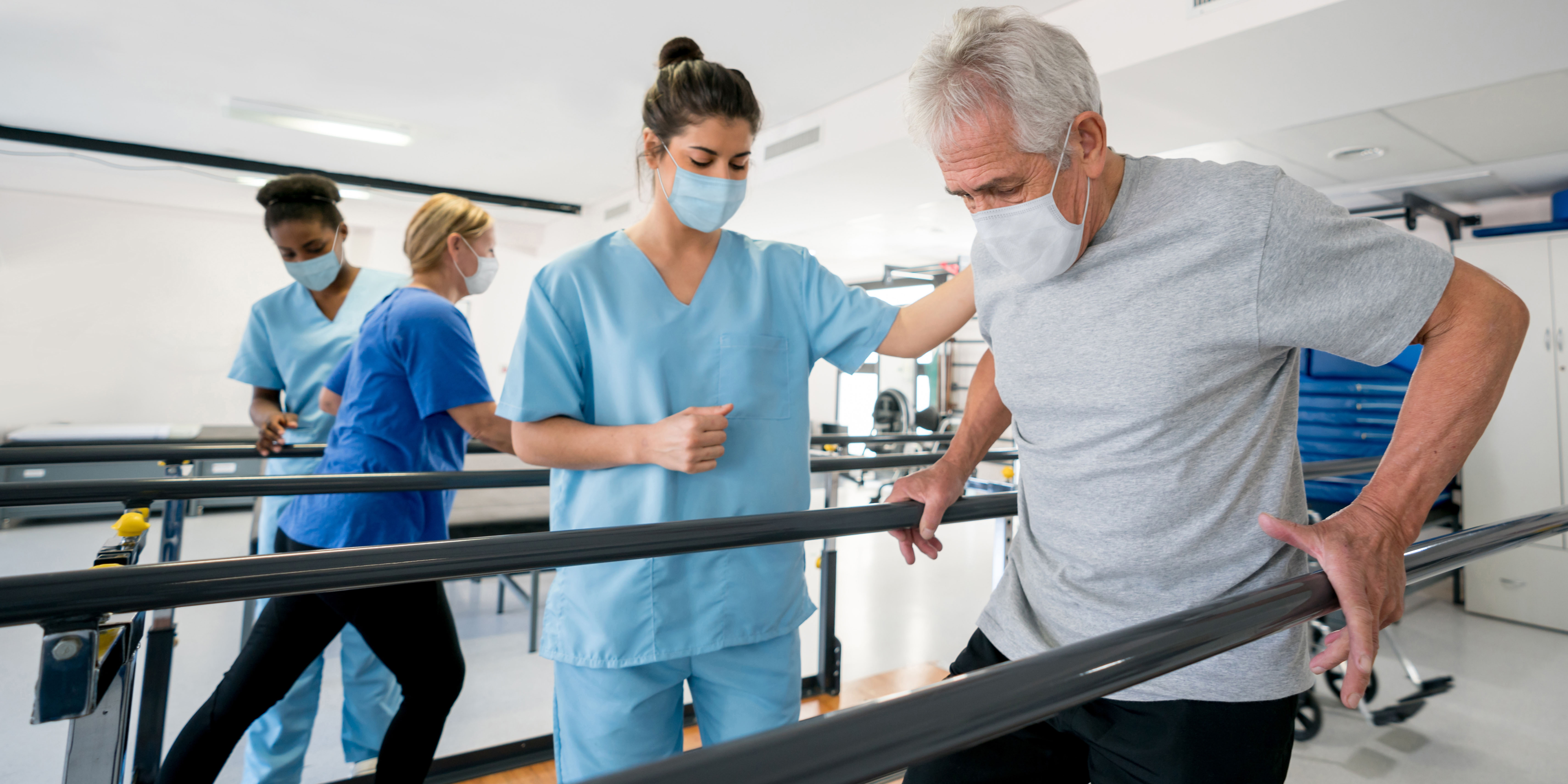 Group of doctors and patients in a rehab center wearing facemasks while doing their physiotherapy