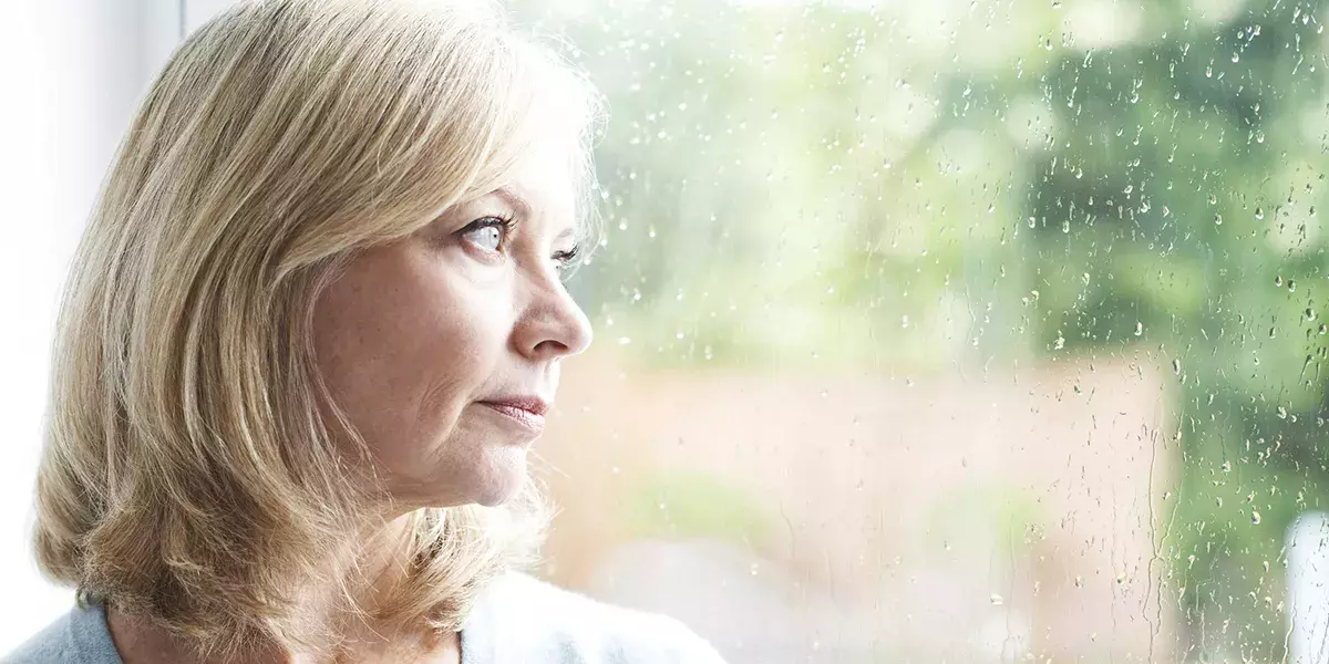 Sad Mature Woman Suffering From Agoraphobia Looking Out Of Windo