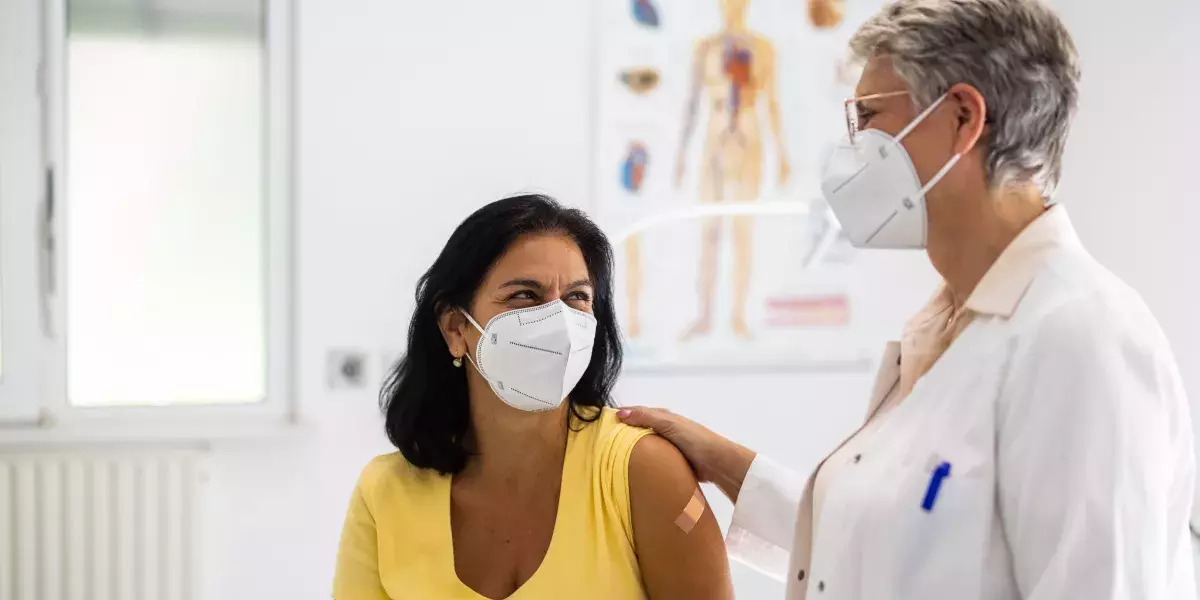 Senior doctor talking with female patient in clinic during pandemic