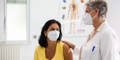 Senior doctor talking with female patient in clinic during pandemic
